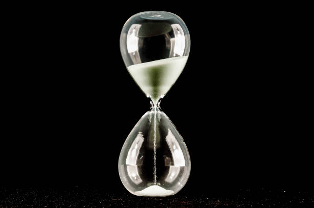 istock A glass hourglass with sand in it is shown on a black background 2151700455