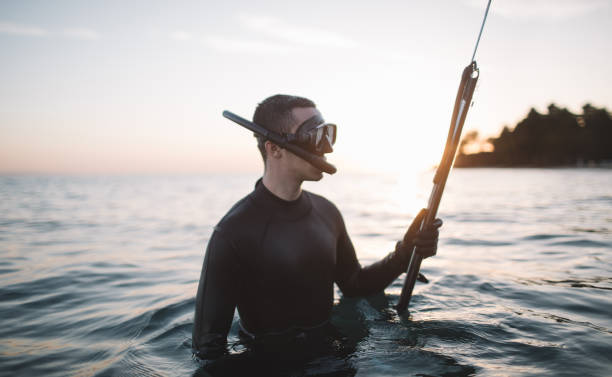 istock Young active man in wetsuit holds a speargun 2151701241