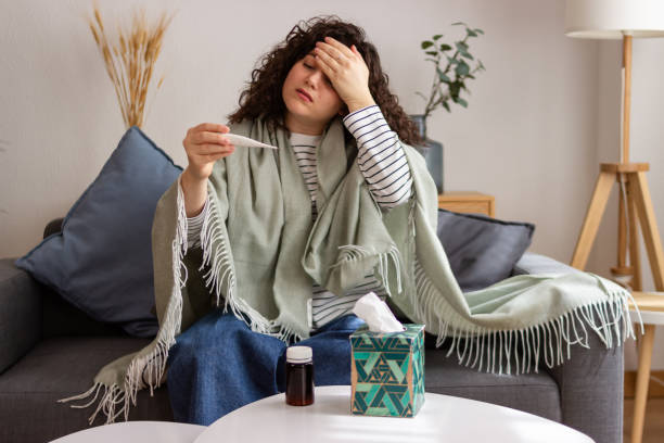istock Sick woman checking temperature on couch 2151706691