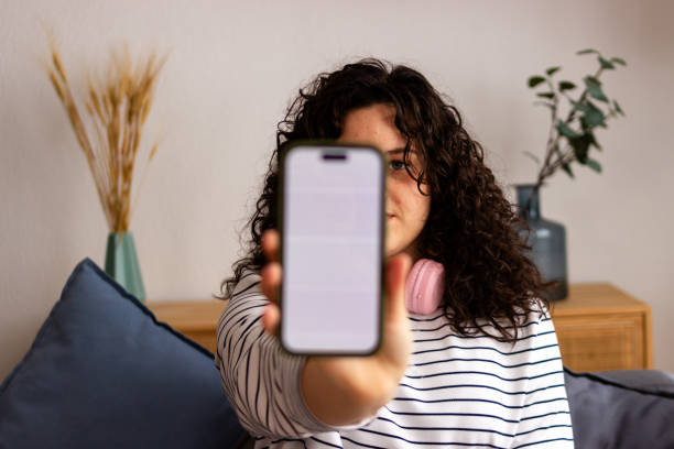istock Young woman showing smartphone screen indoors 2151706773