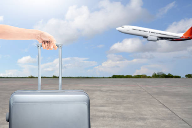 istock A human hand holding a suitcase with an airplane flying on a blue sky background. Ready for traveling 2151706810