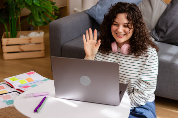 istock Young woman waving hello during video call at home 2151706975