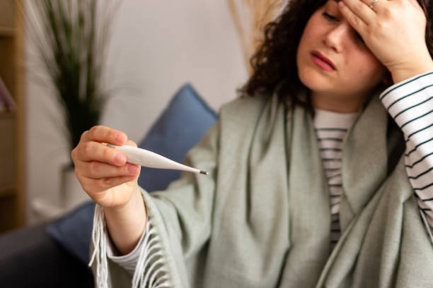 istock Woman with fever checking thermometer 2151707389