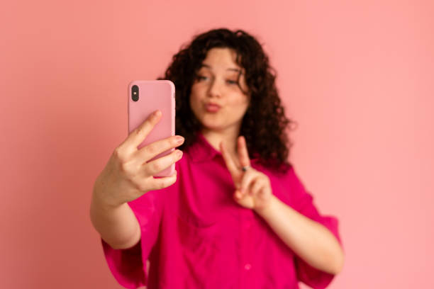 istock Woman taking selfie with smartphone on pink background 2151711949