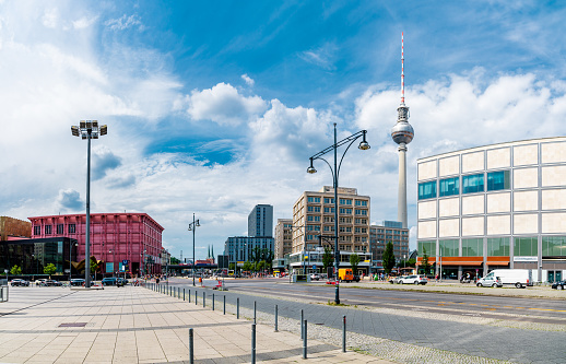 Berlin’s TV Tower Fernsehturm against a backdrop of modern buildings, bustling streets, and a clear blue sky.