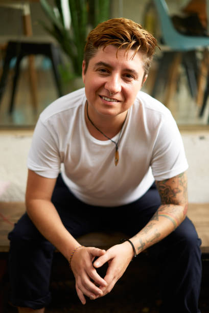 istock Confident transgender pro sits in an urban office setting, smiling and relaxed. Modern workspace design with casual indoor plants. Inclusive work culture, happy LGBTQ employee. 2151721803