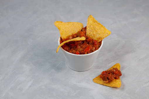 Chili con carne. Tex-mex food. Mexican spicy dish with red beans, peppers, tomatoes and minced meat. Delicious spicy Chili con carne with tortilla chips.