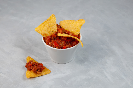 Chili con carne with tortilla chips. Tex-mex food. Traditional Mexican spicy dish with red beans, peppers, tomatoes and minced meat.