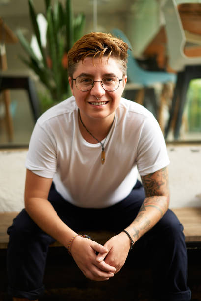 istock Confident transgender man in casual clothes smiles at camera, modern office environment. Inclusive workplace, corporate diversity. Professional portrait, gender identity pride, LGBTQ friendly. 2151722788