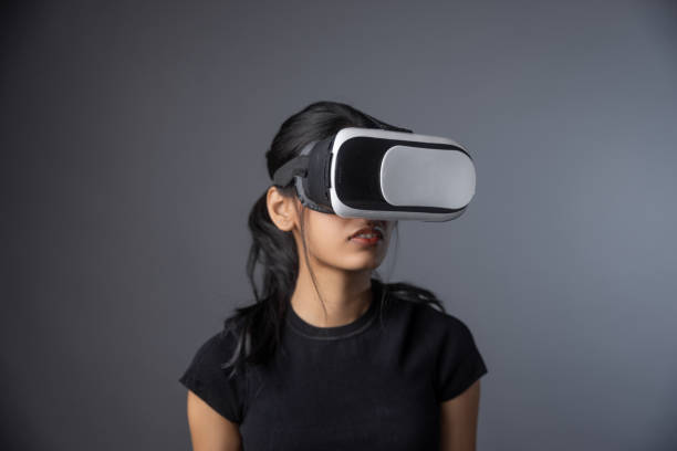 istock Young girl wearing a generic VR headset in front of a grey background 2151722877