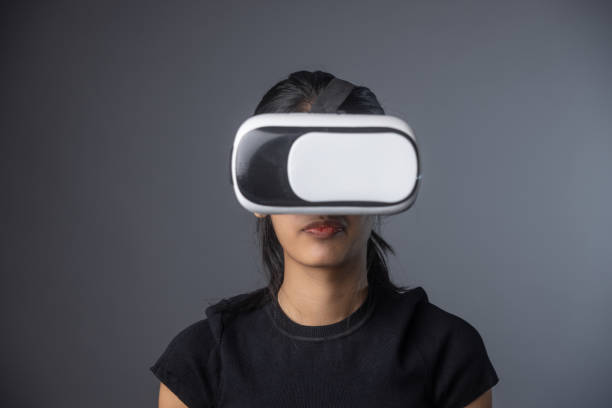 istock Young girl wearing a generic VR headset in front of a grey background 2151722928