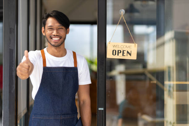 istock A young man a small start-up business entrepreneur who started a small restaurant. A waiter waits for a customer at the door of a coffee shop. 2151726873