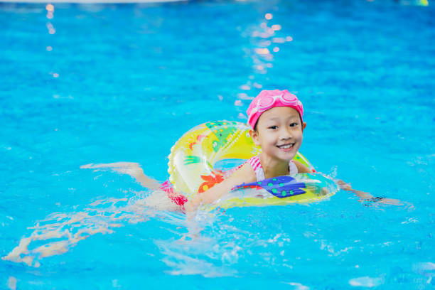 istock Asian girl playing with water in swimming pool while practicing how to swim 2151726978