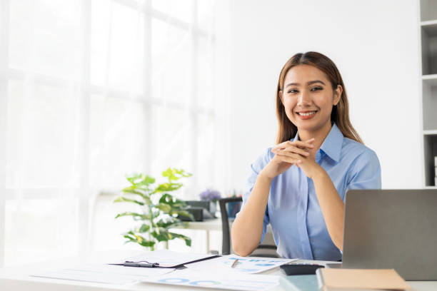 istock Beautiful Asian female accountant smiling while working with laptop and documents about finance, mathematics, accounting reports, statistics. and research ideas 2151733948