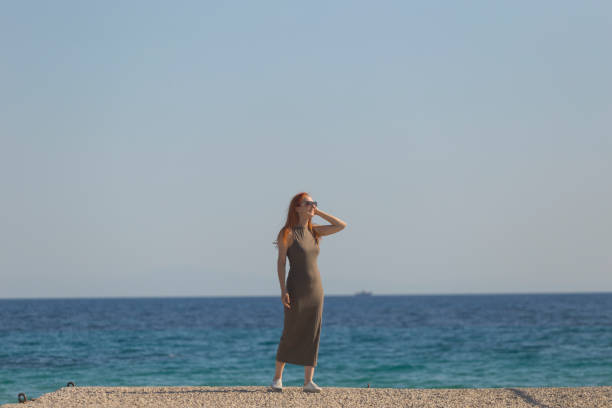 Beautiful woman in long dress enjoy sunset at sea
