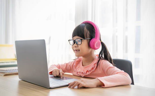 istock Portrait of Asian girl using computer to learn lessons in elementary school. Student nerd glasses girl study in primary. Children gadgets in classroom. Education knowledge, technology internet network 2151735104