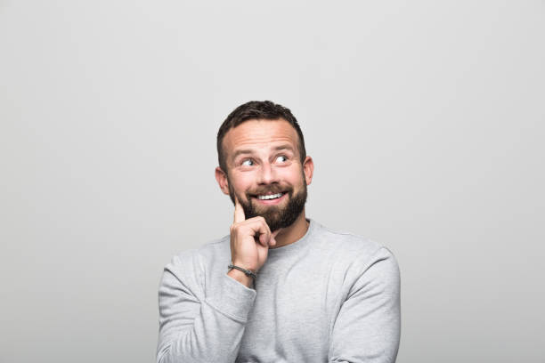 istock Portrait of surprised bearded young man looking up, grey background 2151737302