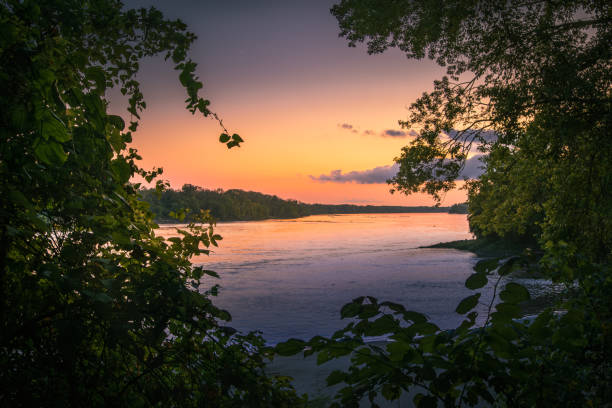View of sunset on Missouri river framed by waterfront trees; sunlight reflect in water