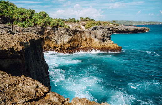 Stunning landscape view of rugged cliffs and vibrant turquoise waters along the coast of Nusa Penida, Indonesia. Ideal for travel and nature themes.