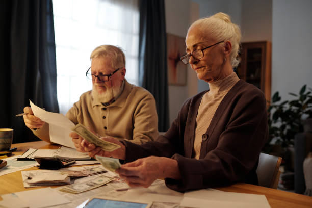 istock Senior woman counting money by table 2151756101