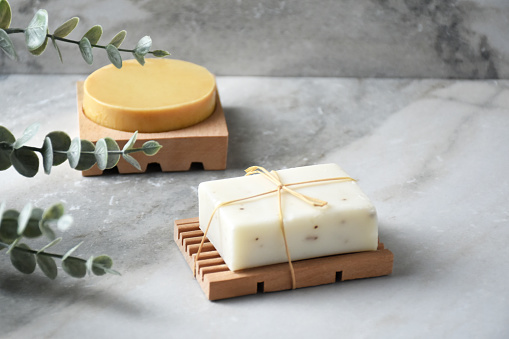 Natural soap bars on marble background with plants and copy space