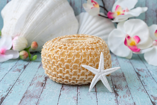Beige sisal shower sponge decorated with seashells and orchids. A washcloth made of sisal for the bathroom.  Spa still life.