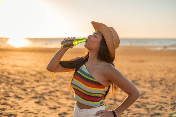 istock Young Multicultural Latin girl Enjoying Beer on Beach at Sunset 2151765658