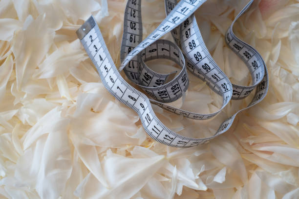 istock White measuring tape on a light background. Tool for measuring length and volume. Tape for measuring in the clothing industry or the volume of the human body 2151765923