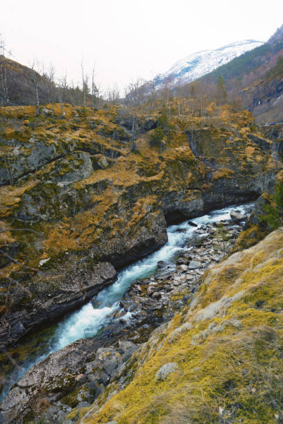 A mountain range with a river running through it. The water is clear and the rocks are grey