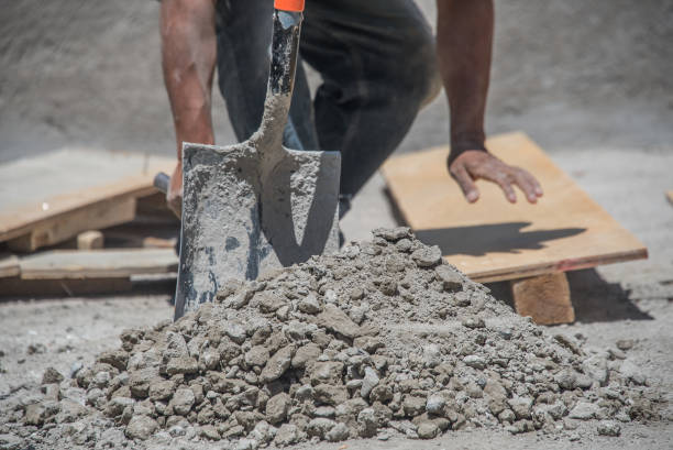 A man is shoveling dirt into a pile. The pile is large and the man is using a shovel to move the dirt