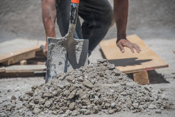 A man is shoveling dirt into a pile. The pile is large and the man is using a shovel to move the dirt