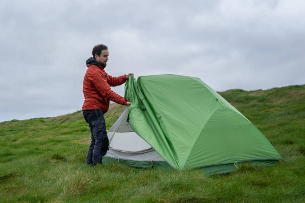 istock explorer setting up his tent on a camping spot 2151776928