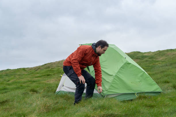 istock man setting up his tent for camping on the field 2151776935