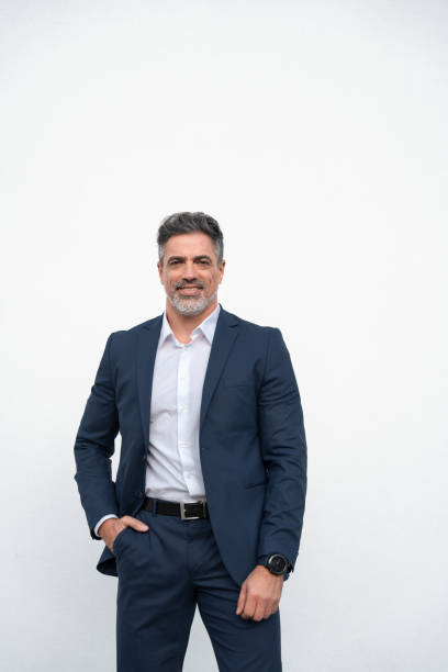 istock Smiling senior business leader man standing proudly, looking at camera on isolated white background. Confident portrait 40s mature successful businessman freelance entrepreneur in suit, vertical. 2151777342