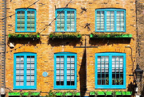 London, United Kingdom - April 29, 2024: Orange facade with blue windows at Neal's Yard, a colorful and vibrant alley in the Covent Garden area of London. House of Monty Python