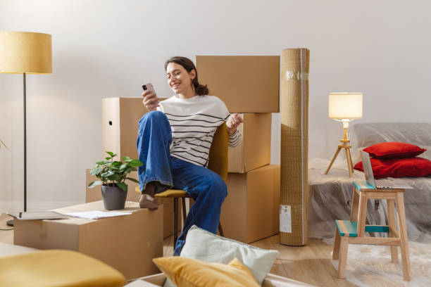 istock Young woman using smart phone in her new apartment 2151791123