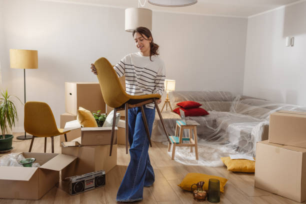 istock Smiling young woman surrounded by boxes while moving, unpacking personal belongings 2151791617