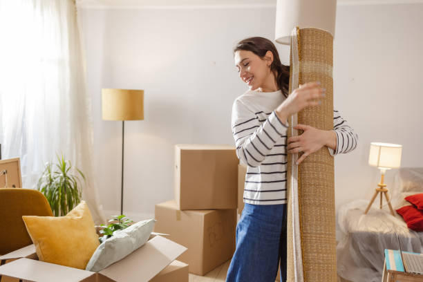 istock Young woman carrying carpet while moving house 2151791698