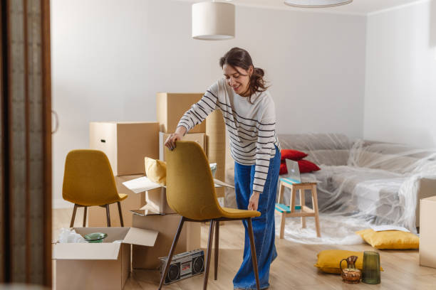 istock Smiling young woman surrounded by boxes while moving, unpacking personal belongings 2151792661