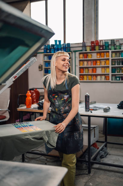 istock Female print shop worker silkscreen printing at workshop. 2151795772