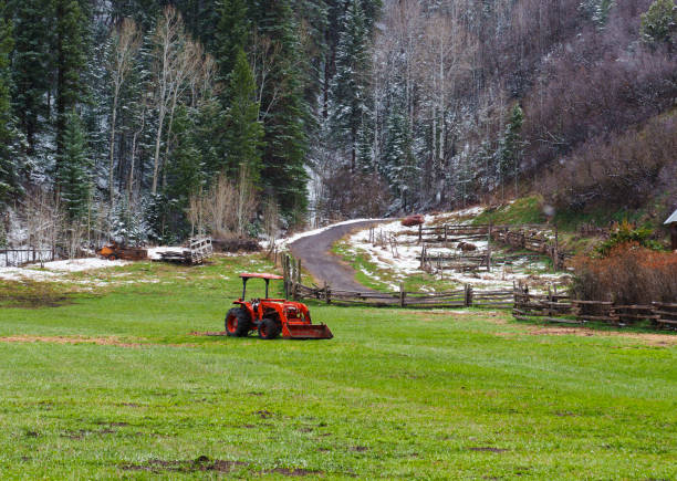Red Farm Tractor in Field with Snow Dusting - Rural scenic in springtime after a fresh light snow storm.