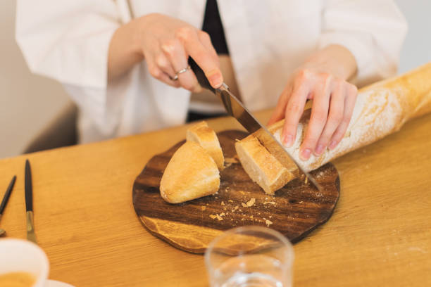 istock Woman slicing baguette in the kitchen. 2151801145