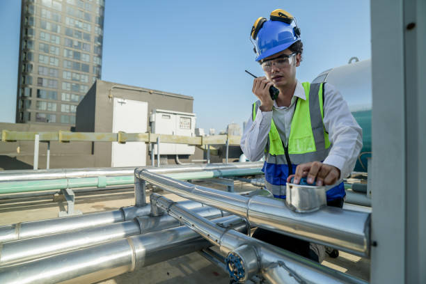 istock Service engineer in protective gear working on heating and cooling systems atop a city building, surrounded by metallic ductwork under the midday sun 2151806073