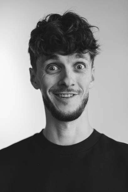 positive handsome man laughing on black background. black and white. copy space