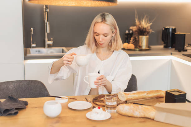 istock Young blonde woman pours cream into coffee. 2151810086