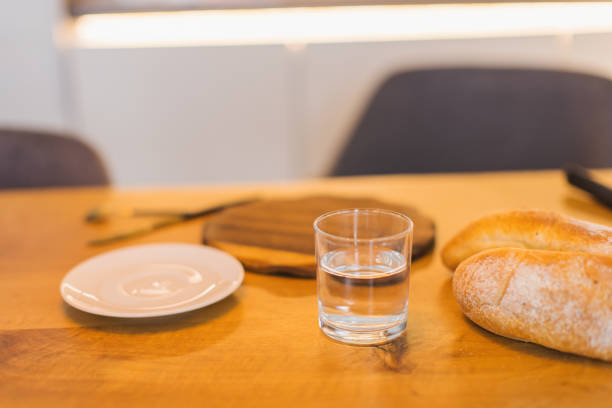 Breakfast. Glass of water on the table. Fresh baguette