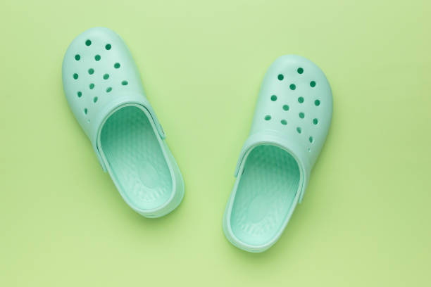 A worn plastic garden clog against a bright background