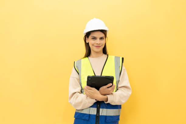 istock Female technician holding a digital tablet and smiling into the camera on yellow studio background 2151829993