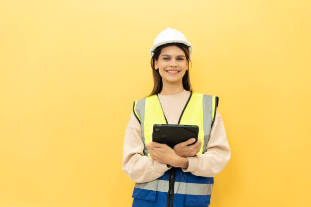 istock Female technician holding a digital tablet and smiling into the camera on yellow studio background 2151829998
