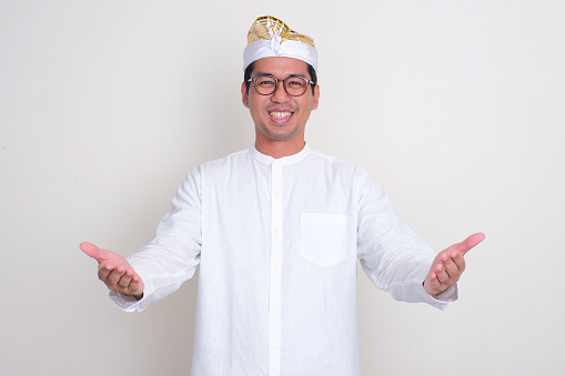 Balinese man smiling at the camera with both hands opened doing welcoming pose